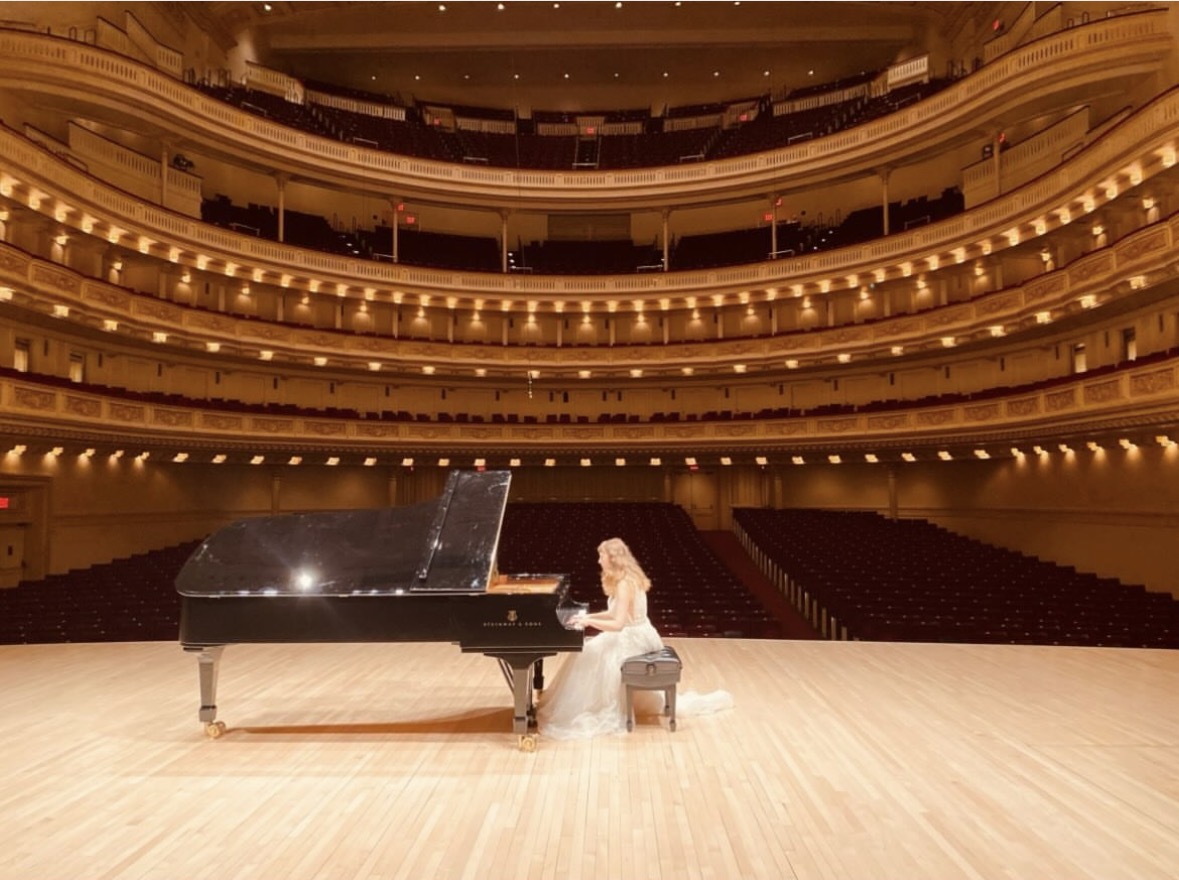 Katya Grineva alone at a grand piano on the Carnegie Hall stage